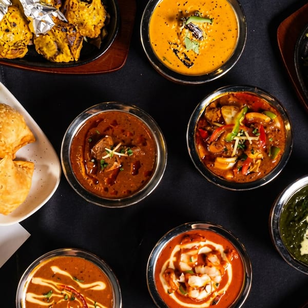 Overhead view of various Indian dishes, including tandoori chicken, samosas, and different curries.